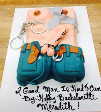 A cake shaped like a mans torso with fondant overalls and handcuffs, featuring the message A Good Man Is Hard To Cum By. Happy Bachelorette Meredith!.